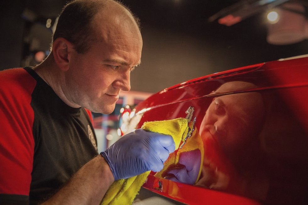 Finn polerer lakken på en rød Ferrari for hånd